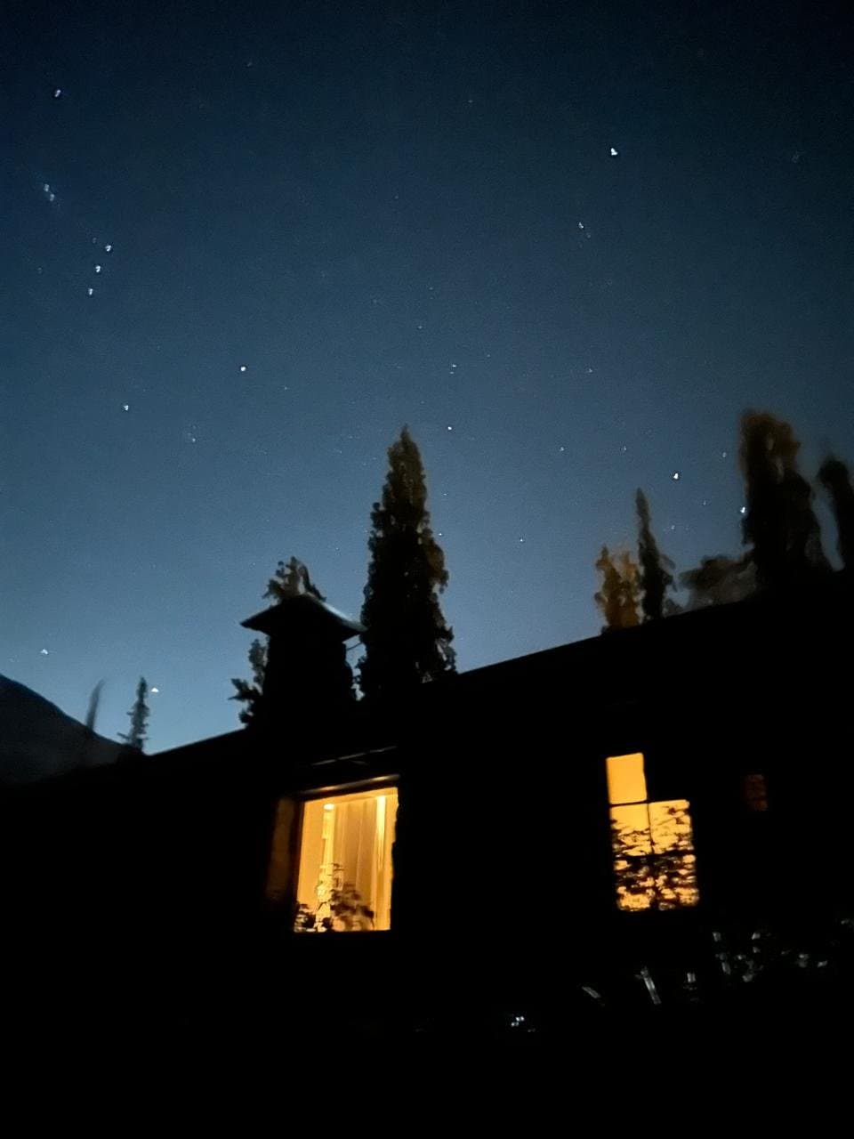 La casa de piedra de noche, con las ventanas encendidas bajo las estrellas